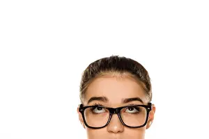 Beautiful Woman Prints: Young confused woman with glasses looking up on white background