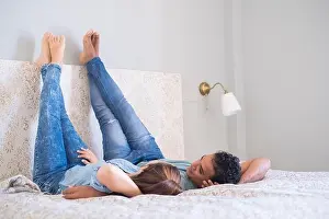 Young couple boy and girl lay down on bed in the bedroom at home or hotel - love and relationship happy couple together in the morning - real lifestyl