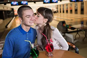 Kissing Prints: young couple sitting and kissing at the bowling bar