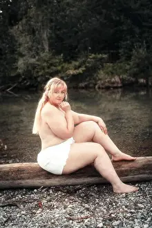 Well Being Prints: Young curvy woman sits scantily clad on a lake on a tree trunk