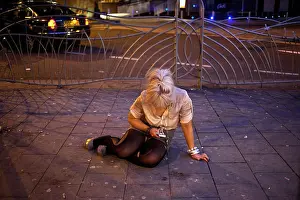 Texting Prints: A young drunk woman sitting on a pavement ans texting sms on her mobile phone on a night out in Cardiff