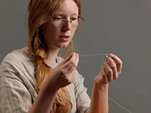 Ponytail Prints: Young female designer threading a sewing needle