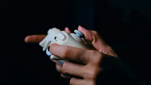 Illuminate Prints: Young female gamer with gamepad or joystick playing video game in dark room