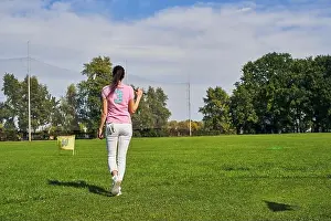 Sportswoman Prints: Young female player walking over the golf course