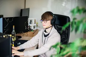 Gamer Prints: Young gamer playing a video game on pc wearing headphones