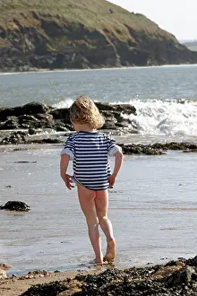 Young girl child Olivia with bare bottom playing in the sand and sea on Daymer Beach near Rock Cornwall