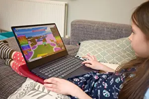Creating Prints: Young girl playing Roblox on laptop computer