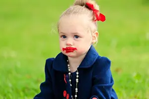 Lipstick Prints: a young girl sits with a dirty face in red lipstick