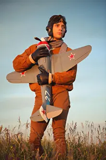 Goggles Prints: Young guy in vintage clothes pilot with an airplane model outdoors