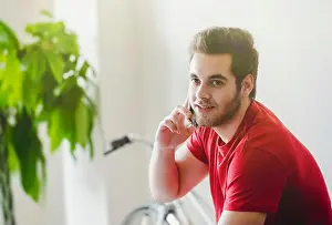 Phoning Prints: Young handsome bearded man in glasses talking on smartphone at home