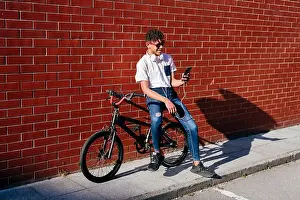 Sneakers Prints: Young happy black male browsing smartphone on bike