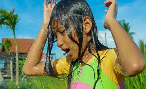 Swimsuit Prints: young happy and carefree beautiful child 7 or 8 years old outdoors having shower at a beautiful rice terrace playful