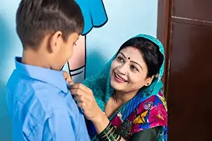 Class Prints: Young happy indian mother wearing sari getting her son ready for school