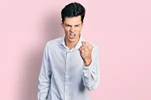Punching Prints: Young hispanic business man wearing business clothes angry and mad raising fist frustrated