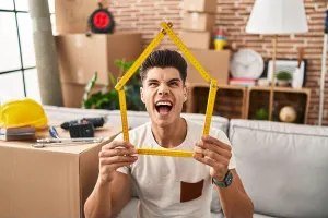 Furious Prints: Young hispanic man moving to a new home angry and mad screaming frustrated and furious