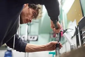 Repairman Prints: Young hispanic man servicing a bicycle in his repair shop