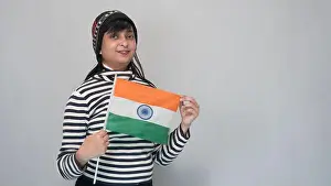 Captivating Prints: Young Indian girl holding national flag, wearing a black a white striped sweater