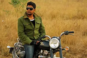 Young in Indian man posing by a royal enfield bullet; Bangalore India
