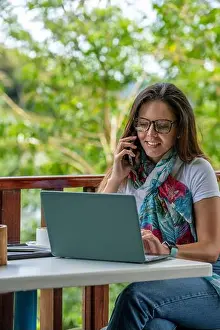 One Young Woman Only Prints: Young Latin American woman working on her laptop at a outdoor cafe while drinking a cup of coffee