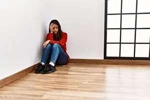 Apartment Prints: Young latin woman with serious expression sitting on the floor at empty room