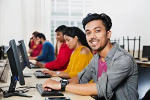 Groups Or Crowds Prints: Young Male College Student Using Computer Studying E-Learning Education With Students In Computer Class