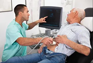 Competence Prints: Young male doctor using ultrasound scan doing abdominal diagnostic to senior male patient in modern clinic