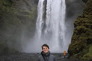 Feel Prints: Young male tourist aged 20-25 poses in front of skogafoss waterfall in Iceland
