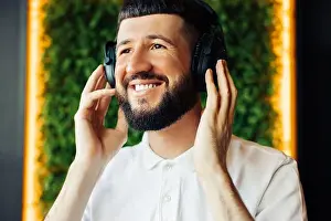 Serious young man with a beard, wearing headphones sitting in a cafe, Favorite music increases my productivity