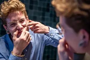 Prevent Prints: Young man bursting a pimple in front of a mirror in a bathroom