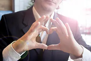 Toned Prints: Young man in business suit in cafe showing thumbs up hand sign heart