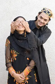 Young Couple Prints: Young man covering a young woman's eyes from behind