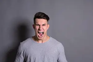 Intense Prints: Young Man Expressing Strong Emotions With a Fierce Shout Against a Plain Background