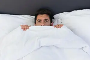 Awake Prints: A young man is hiding in bed under a blanket at home