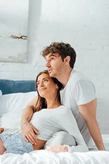 Pajamas Prints: Young man hugging girlfriend in pajamas on bed at morning