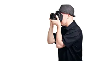 Focusing Prints: A young man looking through the viewfinder of an SLR camera and focusing to take a photo
