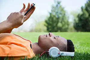 Curly Hair Prints: Young man lying on grass, listening to music
