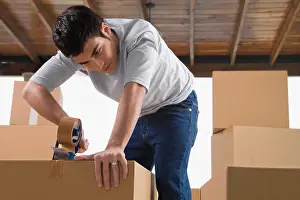 Bending Prints: Young man pasting adhesive tape on a cardboard box