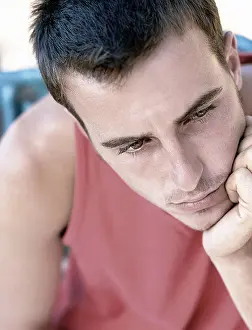 Contemplating Prints: Young man resting his head on his hand with a pensive expression