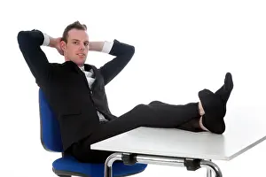 Chill Prints: young man sits on office chair with his feet on table in studio against white background