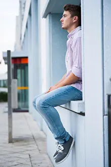 20 25 Prints: Young man sitting on ledge outdoors, Germany