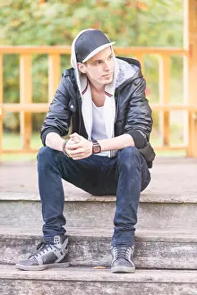 Sideways Prints: Young man wearing a leather jacket, sitting in a park