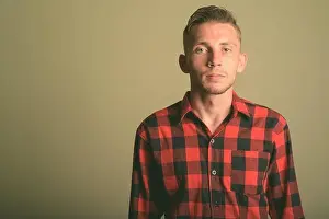 Checkered Prints: Young man wearing red checkered shirt against colored background