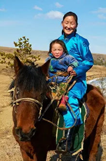Mongolia Prints: Young Mongolian woman and child in traditional costume (deel) riding a horse