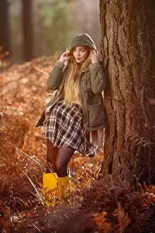 Ferns Prints: Young naturally beautiful women in a forest setting with orange autumnal winter hues wearing a green coat with the hood