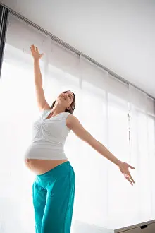 Cheering Prints: Young pregnant woman happy dancing posing
