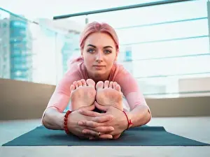 Meditating Prints: Young slim woman with pink dyed hair doing yoga practice on terrace of modern city