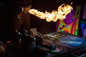 Aerosol Prints: Young street artist finishing his artwork with spray color paint and fire in dark night