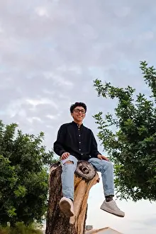 Nightfall Prints: Young transgender man with glasses posing on a log outdoors