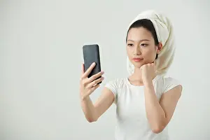 Selfie Prints: Young Vietnamese woman taking selfie on smartphone after shower