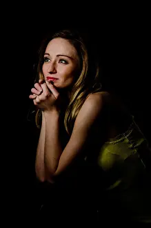 Somethings Prints: Young woman, 25, supporting her head on her hands, sitting in a dark environment